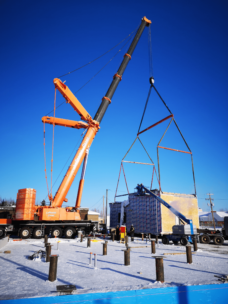 Crane setting a modular unit onto a pile foundation in Yukon